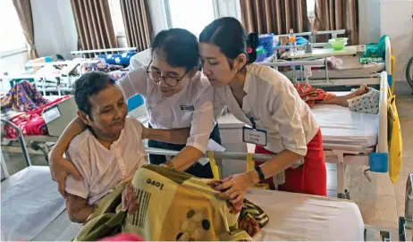  ?? (AFP) ?? This file photo shows an elderly resident of the Twilight Villa nursing home getting help from two nurses to sit up on her bed, in Yangon on July 4