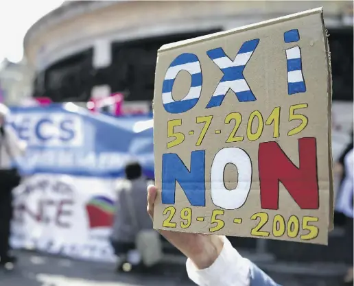  ?? LOIC VENANCE / AFP / GETTY IMAGES ?? A protester holds a sign reading “No” in Greek and French during a rally in support of Greece in Paris on Sunday.
Greece announced capital controls to stave off a financial collapse as anxious citizens emptied cash machines.