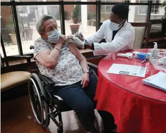  ?? NAncy lAnE PHOTOS / HErAld STAFF FilE ?? ‘ENCOURAGIN­G DATA’: Charlene Monroe gets her vaccine shot from CVS Pharmacy Intern Nick Lubowa at the Ellis Nursing Home in Norwood on Dec. 28, also at left.