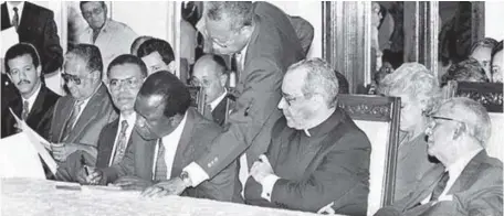  ?? ARCHIVO ?? ↑ Peña Gómez firma, ante la mirada del cardenal López Rodríguez.