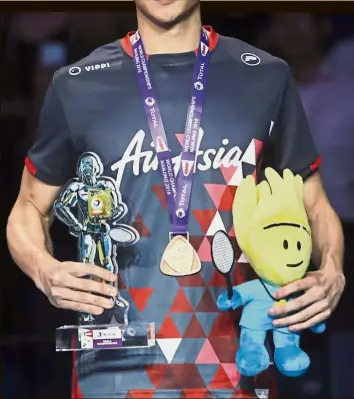  ?? — IZZRAFIQ ALIAS / The Star ?? Something to savour: Malaysia’s Liew Daren posing with his bronze medal at the World Championsh­ips in Nanjing, China. Right: Japan’s Kento Momota kissing his country’s flag on his shirt after beating China’s Shi Yuqi in the men’s singles final.