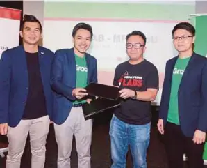  ?? PIC BY SALHANI IBRAHIM ?? Media Prima Digital chief executive officer Rafiq Razali (second from right) exchanging documents with Grab Malaysia country head Sean Goh after the signing of an agreement between the two companies in Kuala Lumpur yesterday. With them are Media Prima Labs &amp; Operation group general manager Nicholas Sagau (left) and Grab business developmen­t head J.J. Tan.