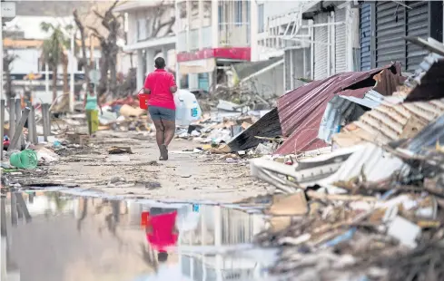  ?? AFP ?? A woman walks on a street in Marigot on the French Caribbean island of St Martin after it was hit by Hurricane Irma.