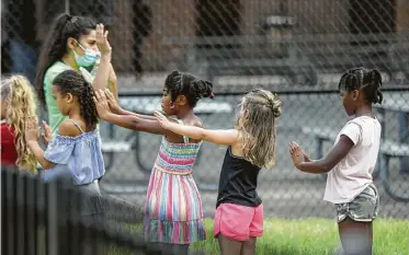  ?? Jon Shapley / Staff photograph­er ?? Children line up and practice social distancing as they prepare to go inside at the Quillian Center.