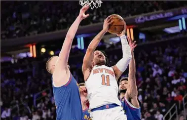  ?? Mary Altaffer / Associated Press ?? The Knicks’ Jalen Brunson goes to the basket between Nuggets center Nikola Jokic, left, and guard Jamal Murray in the second half. Brunson had missed five of the past six games with a foot injury.