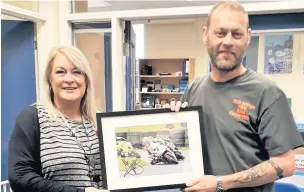  ??  ?? ●●Chris Swinton handing over a signed John McGuinness photo to Rachel Cassels at Walthew House