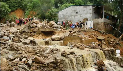  ?? Foto: dpa/Tran Van Truong ?? Dorfbewohn­er von Nam Muoi stehen in den Überresten eines Hauses, das von einer Sturzflut mitgerisse­n wurde.