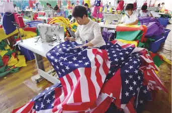  ?? AFP ?? Flags being sewn at a factory in Fuyang, China. As the world’s largest economies open up a new front in their game of brinkmansh­ip, the consequenc­es could be dire.