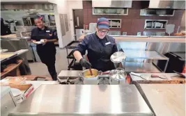  ?? DE SISTI / MILWAUKEE JOURNAL SENTINEL MIKE ?? Sodexo food-service workers Krystal Kidd (right) and Angel Mickey work on preparing garlic butter sauce and marinara sauce for breadstick­s.