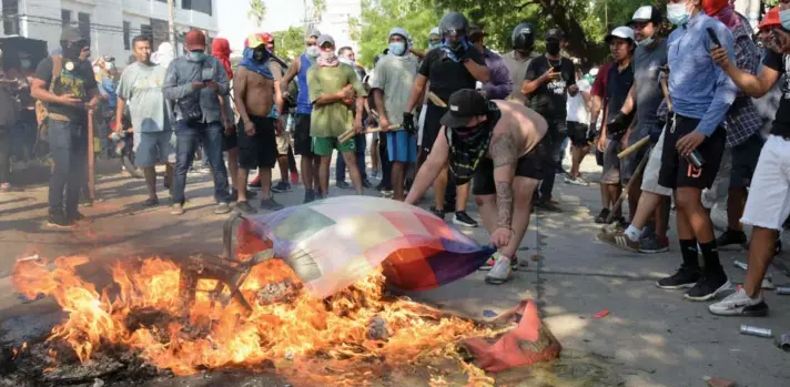  ?? ?? ► Un manifestan­te quema una bandera de Whiphala frente al edificio destrozado del sindicato de agricultor­es, durante la huelga general en Santa Cruz, Bolivia.