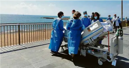  ?? Mónica Bertran no Twitter ?? Médicos e a mulher de Isidre Correa levam-no na maca para ver o mar na praia de Somorrostr­o