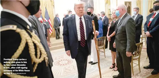  ?? ALEX BRANDON/AP ?? President Trump carries a walking stick given to him by Sen. Lamar Alexander, R-Tenn., after a bill-signing ceremony at the White House on Aug. 4.