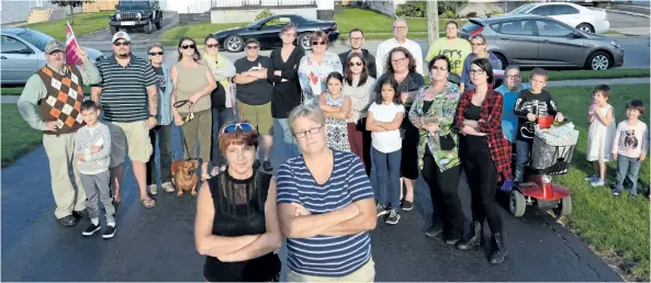  ?? DAVE JOHNSON/ WELLAND TRIBUNE ?? With a group of supporters behind them, Debbie Griffiths, left, and Dawn Greer, right, stand in the driveway of their David Street home where a homophobic message was painted on the door last week. The couple say it’s not the first time they’ve faced...