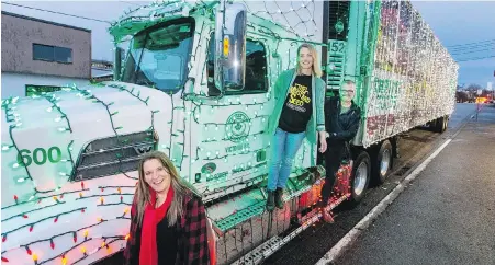  ??  ?? Kelly Kurta, executive director of the Greater Victoria Festival Society, Desiree Neufeld and Derek Pace show off a well-lit Thrifty Foods truck at the Mustard Seed Street Church that will join this evening’s Island Farms Santa’s Light Parade.