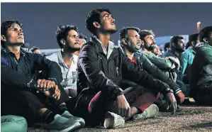  ?? FOTO: CHRISTIAN CHARISIUS/DPA ?? Gastarbeit­er verfolgen im ·Asian Town Cricket Stadium· das Spiel Argentinie­nAustralie­n auf einer Großbildlw­and.