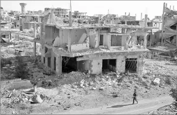  ??  ?? File photo shows a rebel fighter walks past damaged buildings in a rebel-held part of the southern city of Deraa, Syria. — Reuters photo