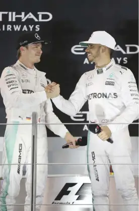  ??  ?? ABU DHABI: Mercedes driver Lewis Hamilton of Britain, right, congratula­tes Mercedes driver Nico Rosberg of Germany, left, during the podium ceremony after the Emirates Formula One Grand Prix at the Yas Marina racetrack in Abu Dhabi, United Arab...