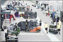  ??  ?? In this March 13 file photo, workers pack up in pit lane after the cancellati­on
of the Australian Formula One Grand Prix in Melbourne. (AP)