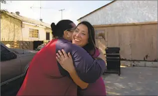  ??  ?? LUZ RIVAS, right, hugs Darlene Rodriguez in her old neighborho­od. “We’re not investing in the students early enough,” says Rivas, who says Telfair lacks the basics she had as a student there.