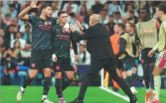  ?? AFP ?? Phil Foden (center) and Ruben Dias walk toward manager Pep Guardiola to celebrate after Foden netted Manchester City’s second goal in Tuesday’s 3-3 draw with Real Madrid.