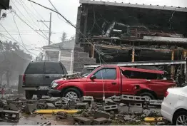  ?? Scott Olson / Getty Images ?? A partially collapsed building leaves debris on a pickup after Hurricane Ida blew strong winds into New Orleans. The entire city was in the dark late Sunday.