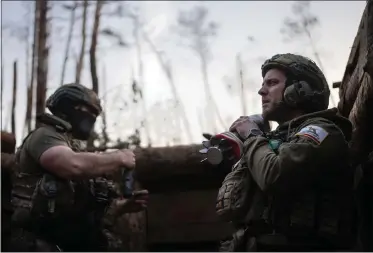  ?? ALEX BABENKO — THE ASSOCIATED PRESS ?? A Ukrainian serviceman from the Azov brigade known by call sign Chaos, right, carries a mortar shell while he waits for a command to fire about a half mile away from Russian forces on the frontline in Kreminna direction Friday in Donetsk region, Ukraine.