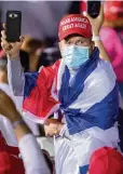  ?? DANIEL A. VARELA dvarela@miamiheral­d.com ?? A Trump supporter wrapped in a Cuban flag looks out toward the crowd during the Make America Great Again Victory Rally on Nov. 1.