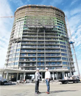  ?? JOEL CEAUSU, SPECIAL TO THE MONTREAL GAZETTE ?? Brothers George (at left) and Jack Saroukian pose in front of the first of six 22-storey buildings that will comprise Laval’s Central Parc developmen­t; they say constructi­on is ahead of schedule, with the entire project expected to be finished within four years.