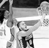  ?? AJ MAST/AP ?? Oral Roberts’ Kevin Obanor (0) drives to the basket by UF forward Anthony Duruji, left, as Obanor scored two of his 20 second-half points during the Golden Eagles’ 81-78 comefrom-behind win Sunday during the second round of the NCAA Tournament.