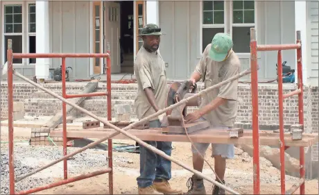  ??  ?? Rome News-Tribune SUNDAY, Duke Mathis (left) and Jim Waldrop, with M Brick Co. of Cedartown, cut bricks for this home being built by K.C. Homes in the North Quarters subdivisio­n.