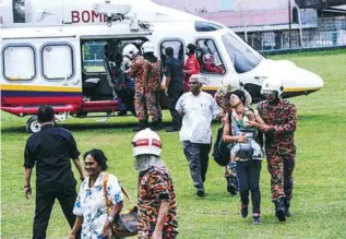  ??  ?? Some of those stranded on Penang Hill disembarki­ng from the helicopter with the help of firemen after being flown to the Federal Reserve Team Unit 3 base in Air Itam.