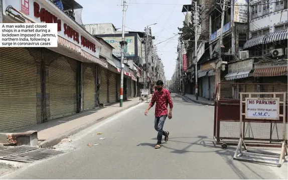  ??  ?? A man walks past closed shops in a market during a lockdown imposed in Jammu, northern India, following a surge in coronaviru­s cases