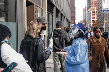  ?? Jeenah Moon / Bloomberg ?? A health care worker assists residents on Dec. 5 at a vaccinatio­n site in the Chinatown neighborho­od of New York. Gov. Kathy Hochul ordered more than 30 hospitals to halt procedures amid a surge in COVID cases.