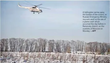  ?? — AFP ?? A helicopter carries away the bodies of the victims, as Russian Emergency Ministry rescuers work at the site of a plane crash which occurred the day before in Ramensky district, on the outskirts of Moscow on Monday.