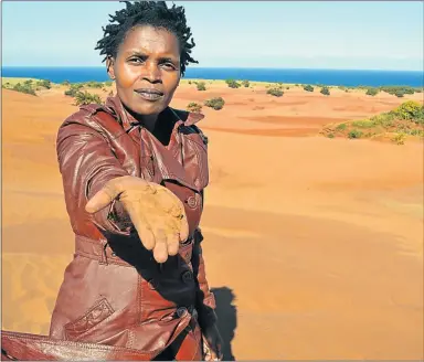  ?? Picture: LOYISO MPALANTSHA­NE ?? MOTHER EARTH: Nonhle Mbuthuma of Amadiba Crisis Committee shows the red sand at Kwanyana Beach near Xolobeni that is at the centre of the dispute