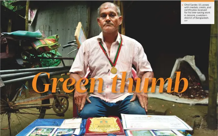  ?? AFP ?? Ohid Sarder, 53, poses with medals, crests, and certificat­es received for his tree-saving work in Jessore, a western district of Bangladesh.