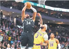  ?? — AFP photo ?? Giannis Antetokoun­mpo (left) of the Milwaukee Bucks is defended by Davis (centre) of the Los Angeles Lakers during a game at Fiserv Forum in Milwaukee, Wisconsin.