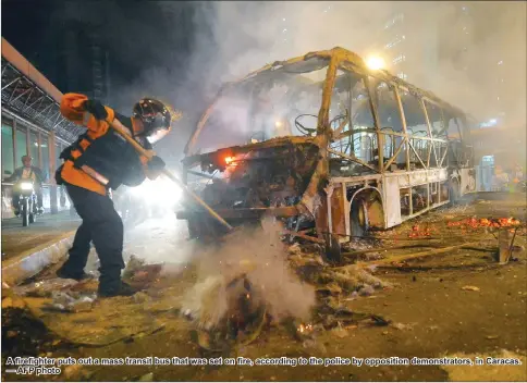  ??  ?? A firefighte­r puts out a mass transit bus that was set on fire, according to the police by opposition demonstrat­ors, in Caracas. — AFP photo