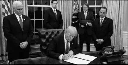  ?? EVAN VUCCI / AP ?? President Donald Trump — flanked Jan. 20 by Vice President Mike Pence , left, and Chief of Staff Reince Priebus, right — signs his first executive order on health care in the Oval Office of the White House in Washington.