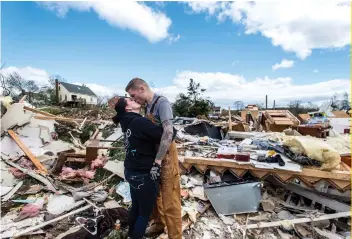  ?? AP FOTO ?? ROMANCE BY THE RUINS: A couple take a moment of respite while clearing debris from a stormdamag­ed home in western Virginia.