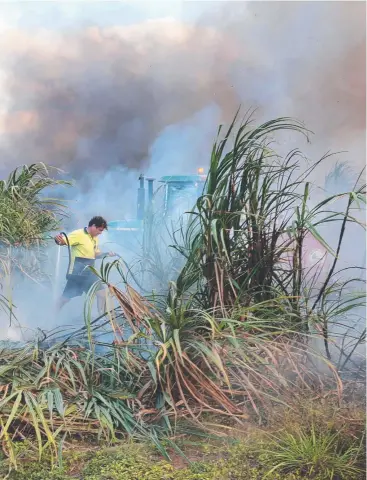  ?? Picture: ANNA ROGERS ?? INTENSE HEAT: Rural fire brigade personnel use a water tank on a tractor to fight the cane fire on Logonmeir Rd, Edmonton.