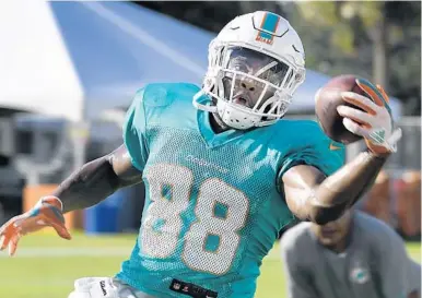  ?? TAIMY ALVAREZ/STAFF PHOTOGRAPH­ER ?? Wide receiver Leonte Carroo makes a one-handed catch during camp. He and a number of other players have a chance to earn a spot on the Dolphins’ 53-man roster with their play beginning tonight.