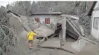  ?? AARON FAVILA/AP ?? A resident passes a house destroyed by volcanic ash in Boso-Boso, Batangas province, southern Philippine­s, on Tuesday.