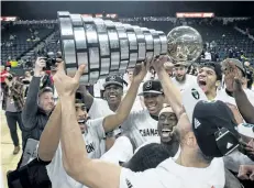  ?? DARREN CALABRESE/THE CANADIAN PRESS ?? Members of the Carleton Ravens men’s basketball team raise the W.P McGee Trophy following their win over the Ryerson Rams in the USports basketball national championsh­ip game Sunday in Halifax.