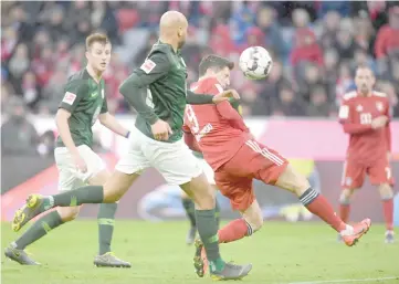  ??  ?? Bayern Munich’s Polish striker Robert Lewandowsk­i (right) scores during the German first division Bundesliga football match Bayern Munich vs VfL Wolfsburg in Munich. — AFP photo