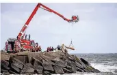  ??  ?? Rettungskr­äfte bergen mit Hilfe einer Rettungswa­nne eine Leiche.