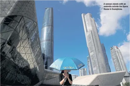  ??  ?? Awoman stands with an umbrella outsidethe Opera House in Guanghzou.