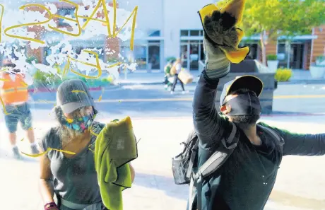  ?? AP ?? Volunteers clean up graffiti on a window at The Pike Outlets, yesterday in Long Beach, California, after overnight protests in reaction to George Floyd’s death on May 25 in Minneapoli­s.