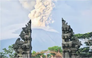  ?? — AFP photo ?? A general view shows Mount Agung erupting between Balinese temple seen at night from Kubu sub-district in Karangasem Regency on Indonesia’s resort island of Bali.