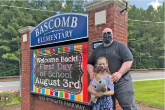  ?? AP PHOTO/JEFF AMY ?? John Barrett and his daughter, Autumn, pose for photos outside Bascomb Elementary School in Woodstock, Ga., on Thursday. Barrett says he will educate his daughter virtually and keep her out of in-person classes in Cherokee County schools.